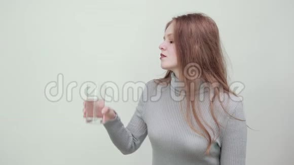 穿灰色毛衣的红头发女人解渴喝一杯水视频的预览图
