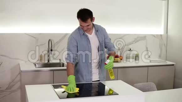 高个子开朗的白种人穿着蓝色衬衫在厨房里打扫卫生用化学药品清洗厨房的炉子视频的预览图
