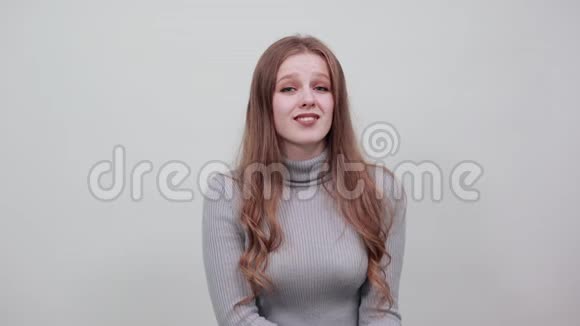 一个穿灰色毛衣的年轻漂亮红头发女人心情愉快视频的预览图