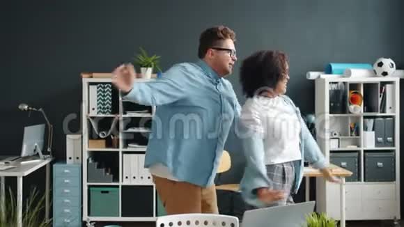 快乐的青年男女在办公室跳舞在工作中一起玩视频的预览图