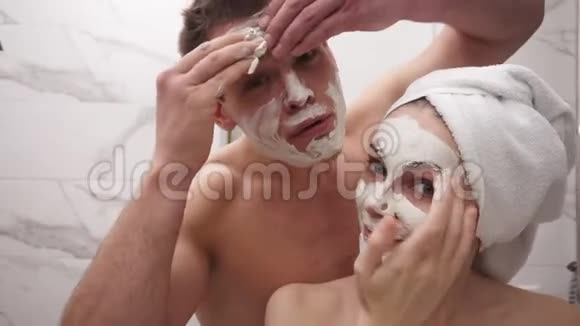 快乐积极的年轻夫妇在淋浴后站在浴室里玩得开心两者都在玩视频的预览图