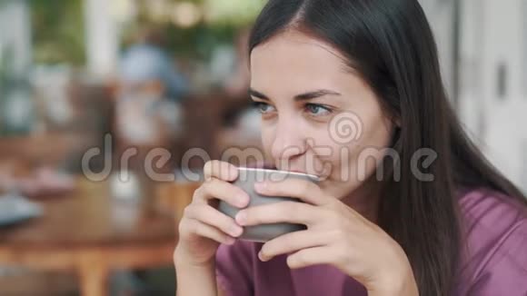 美女在咖啡馆里喝着杯中的热饮料微笑着的肖像视频的预览图