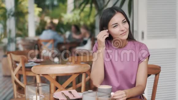 年轻女子戴上无线耳机在咖啡馆里听音乐和跳舞视频的预览图