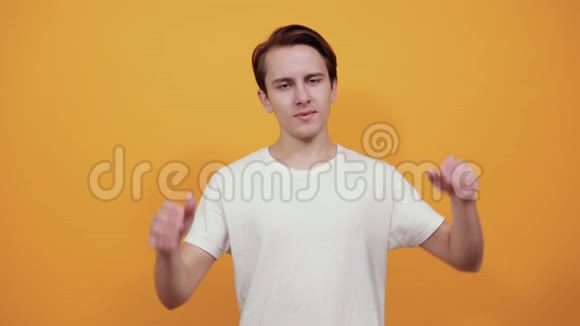 穿白色t恤的年轻人把手放在头后面黄色背景视频的预览图