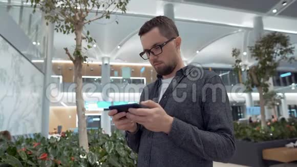 年轻人正在机场候机室玩智能手机视频的预览图