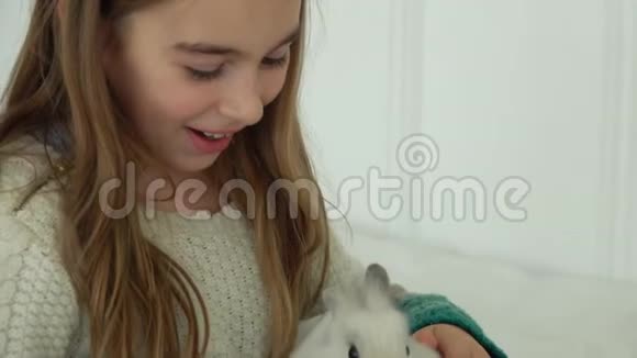 快乐美丽的女孩爱抚可爱的小兔子视频的预览图