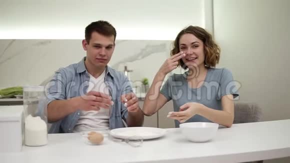可爱的积极夫妇在厨房的脸上涂抹面粉快乐的年轻夫妇在做食物时胡闹视频的预览图