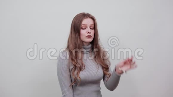 穿灰色毛衣的红头发女人用手指摸着头摆出时髦的姿势视频的预览图