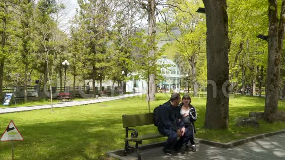 游客们一男一女坐在公园的长凳上视频的预览图