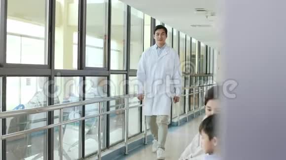 一位亚洲医生在医院走廊上和母子交谈视频的预览图