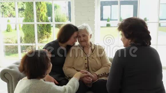一位年长的白发妇女坐在女儿和孙女旁边视频的预览图