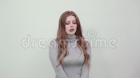一个年轻漂亮的红发女人穿着一件灰色的毛衣看上去很狼狈视频的预览图