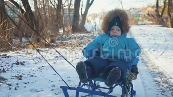 父母在冬天带着快乐的小男孩在雪橇上幼儿玩雪橇家庭圣诞节的户外乐趣视频的预览图
