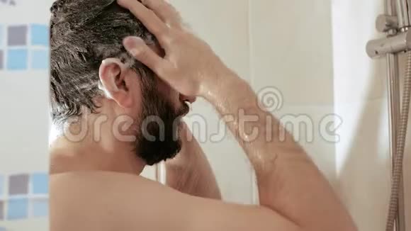 男人正在按摩洗发水浸过的头年轻人洗澡慢动作并关闭视频的预览图