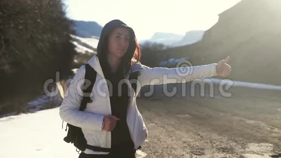 旅游女孩带着一个大背包在一条孤独的乡村道路上搭便车单独的旅程视频的预览图