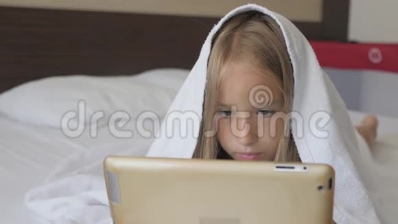 十几岁的女孩在床上玩社交网络上的平板电脑特写小女孩在数字平板上看视频视频的预览图