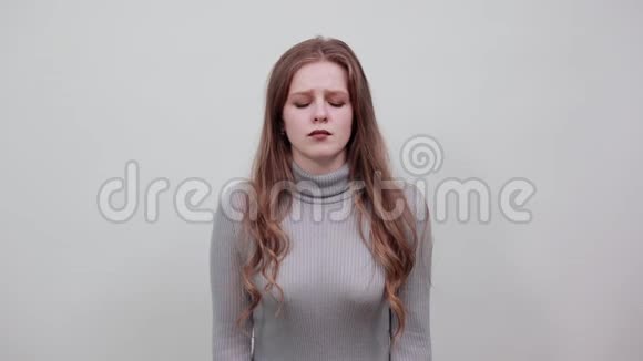 戴着灰色毛衣的红发女人头痛双手抱头视频的预览图