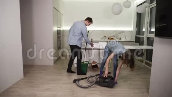 清洁日年轻夫妇准备打扫公寓的工具男人拿着擦拖把女孩准备吸尘器视频的预览图
