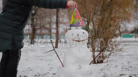 快乐女孩在冬季公园堆雪人寒假和圣诞节的概念视频的预览图