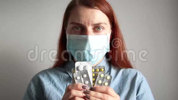 戴着医疗面具的年轻女孩拿着药丸病人拿着水泡吃药视频的预览图