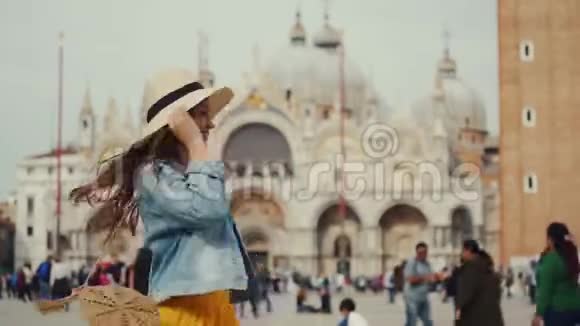 穿帽子的女孩牛仔黄色的裙子在广场上与模糊的圣马可教堂做对比视频的预览图