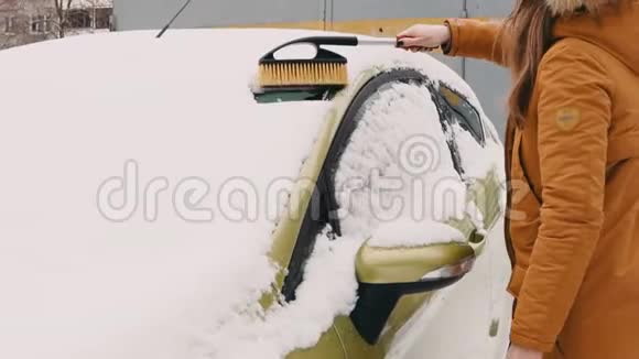 院子里一个穿暖和夹克的女人用扫把刷子把沙拉车从沙拉车清理干净视频的预览图