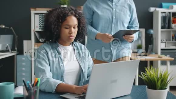 男女办公室工作人员在室内使用笔记本电脑交谈视频的预览图