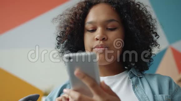 有魅力的女孩手里拿着智能手机在家里摸着彩色背景的屏幕视频的预览图