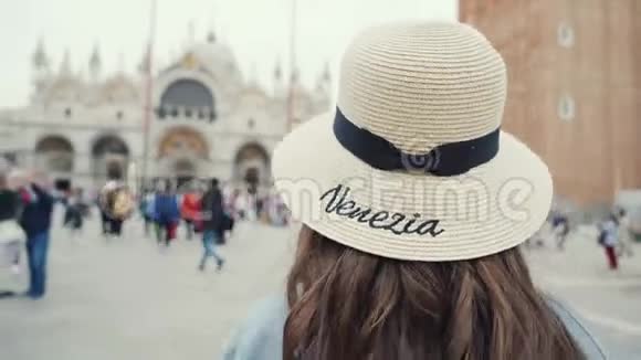 可爱的女孩戴着草帽走在圣马可广场回头看可爱的微笑视频的预览图