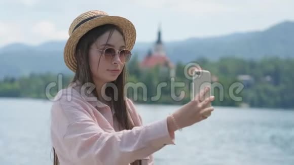 夏天旅行者女用智能手机在布莱德湖上自拍视频的预览图