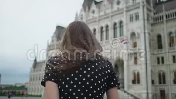 旅行者女孩在匈牙利议会大楼前的广场上奔跑视频的预览图