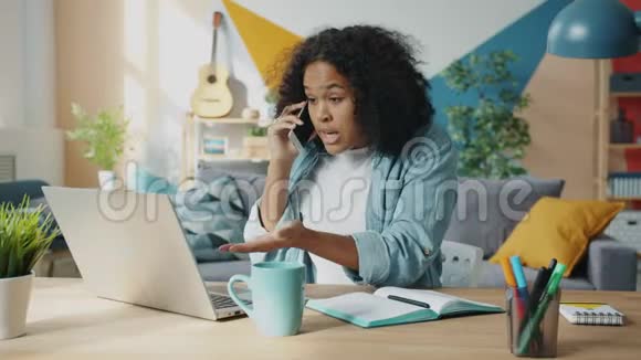 疯狂的非裔美国女人在家里用笔记本电脑在手机上大喊大叫视频的预览图