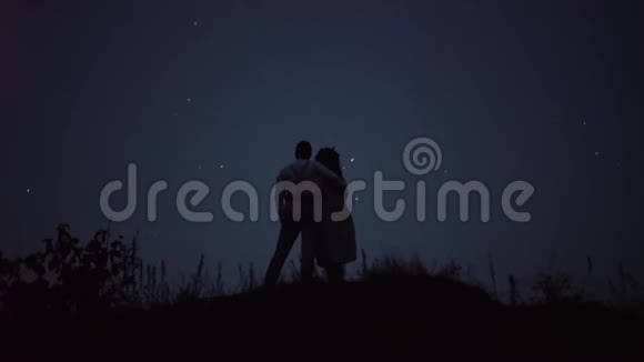 一对浪漫的情侣在山上拥抱对方背景上有星星夜间射击视频的预览图