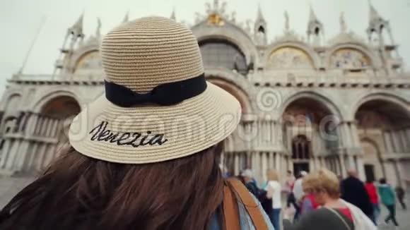 穿帽子的布鲁内特姑娘站在圣马可广场上看着圣马可岛视频的预览图