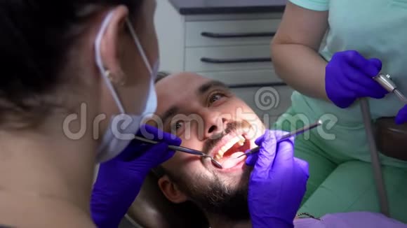 牙医正在用特殊的牙科镜检查一名男性病人的牙齿视频的预览图