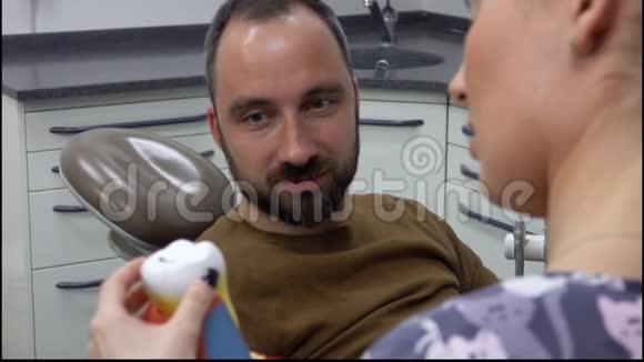 牙医正在给病人展示一种牙齿模型视频的预览图