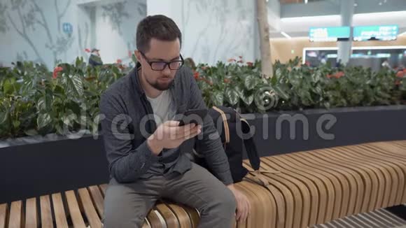 男旅客正在机场用智能手机查看电子邮件视频的预览图
