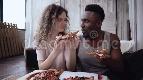 多种族的夫妇在吃饭时玩得很开心女人给男人喂了一片披萨男女吃快餐视频的预览图