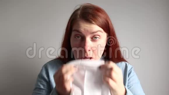 一个穿着蓝色牛仔衬衫的红发女孩把鼻子撞到围巾上病毒概念视频的预览图