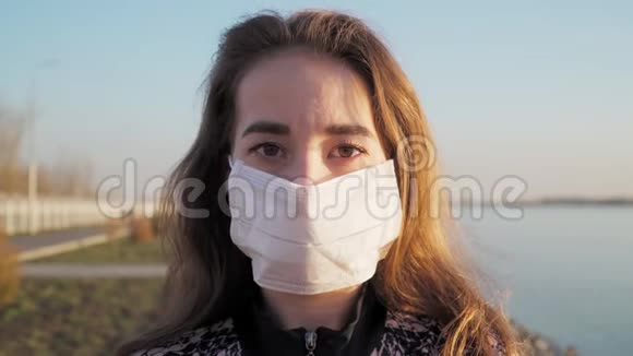 戴着白色医疗面具看着摄像机的白人少女疾病和病毒的主题预防感染视频的预览图