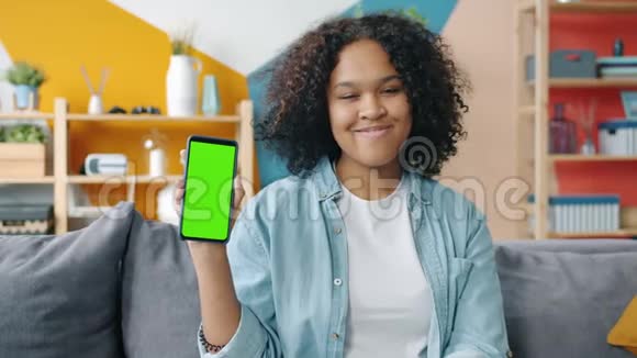 非洲裔美国女孩手持绿色屏幕智能手机看相机的肖像视频的预览图