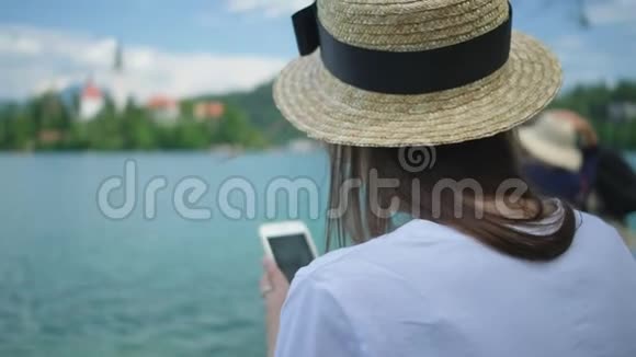 斯洛文尼亚布莱德湖游览时带着手机的旅游妇女视频的预览图