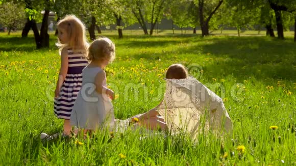 三个穿着漂亮条纹连衣裙的女孩正和狗在花园里玩耍视频的预览图