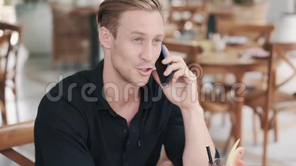 帅哥在咖啡馆打电话喝西瓜汁的画像视频的预览图