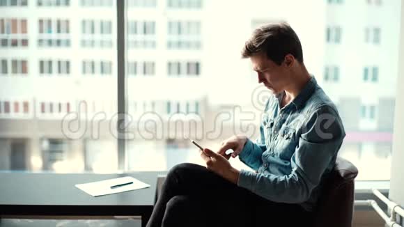 体贴的年轻商人坐在椅子上在办公室里用平板电脑视频的预览图