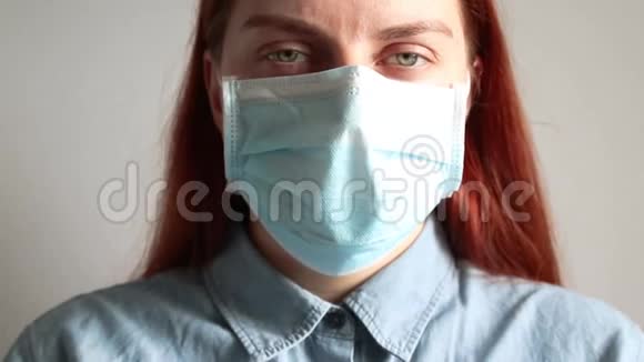 一个戴着医用口罩的红发绿眼的年轻女孩看着镜头病毒保护环境视频的预览图