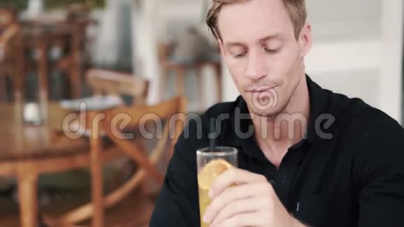 帅哥在咖啡馆喝橙汁的肖像看着镜头微笑视频的预览图