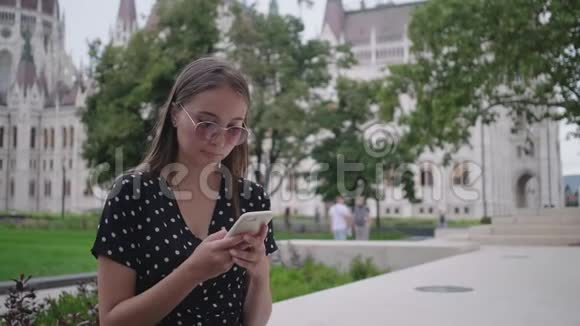 年轻女子在户外用手机发送信息视频的预览图