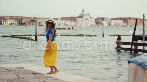 戴帽子的快乐女孩黄裙赤脚奔跑在威尼斯码头嬉戏视频的预览图