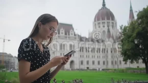 年轻女子在户外的智能手机上阅读信息视频的预览图